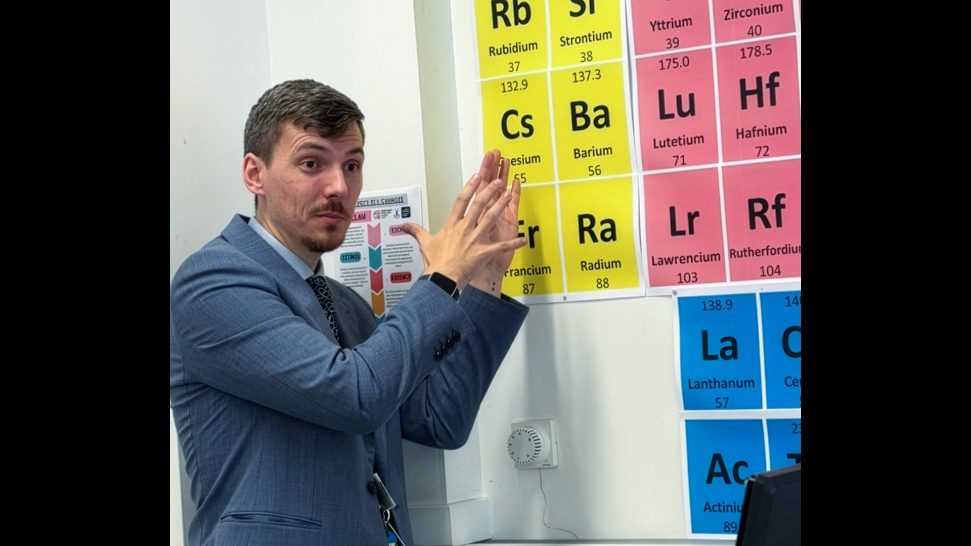 Matthew Gundry in suit and tie explaining periodic table