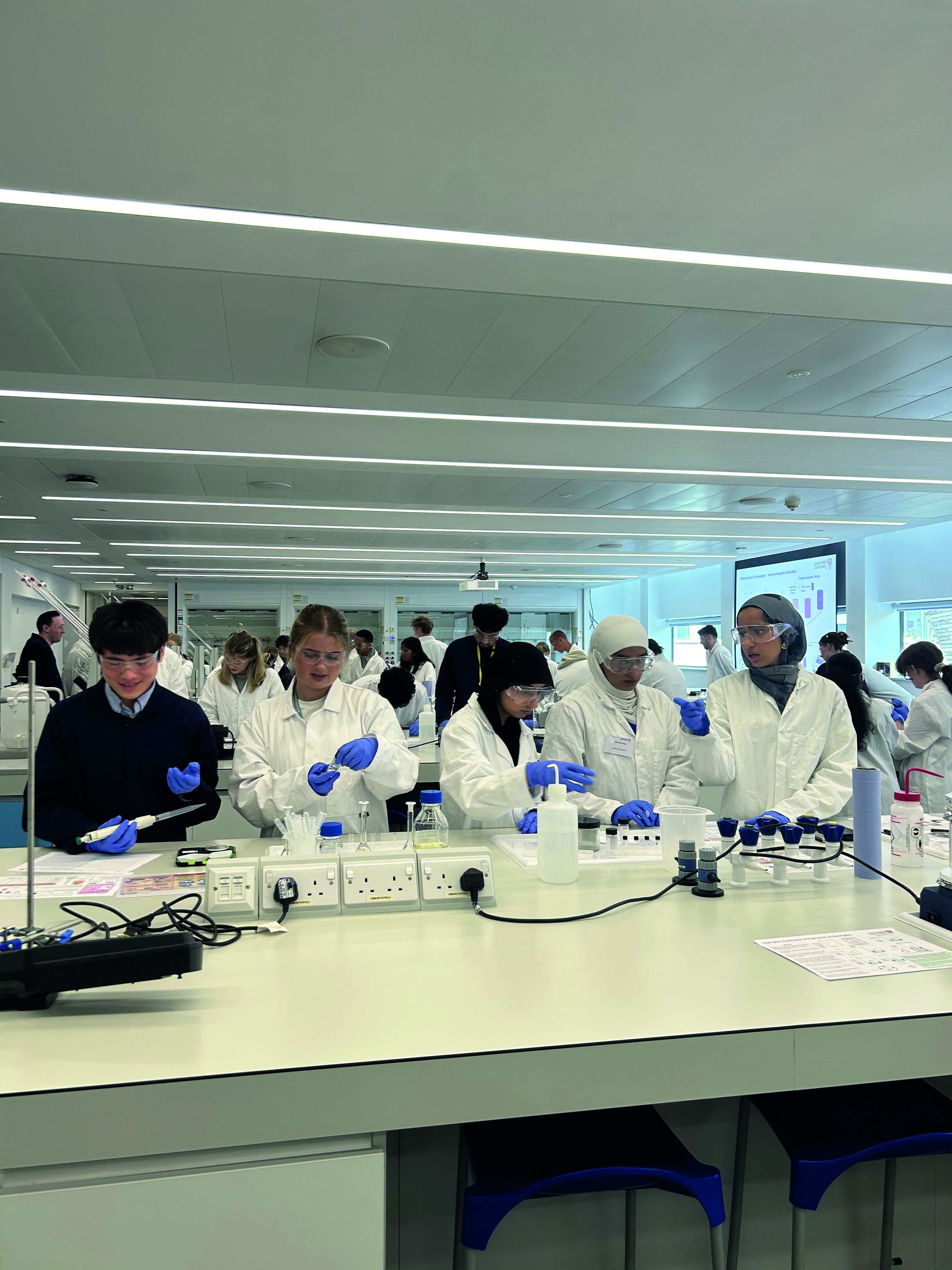 Students wearing safety goggles conduct an experiment
