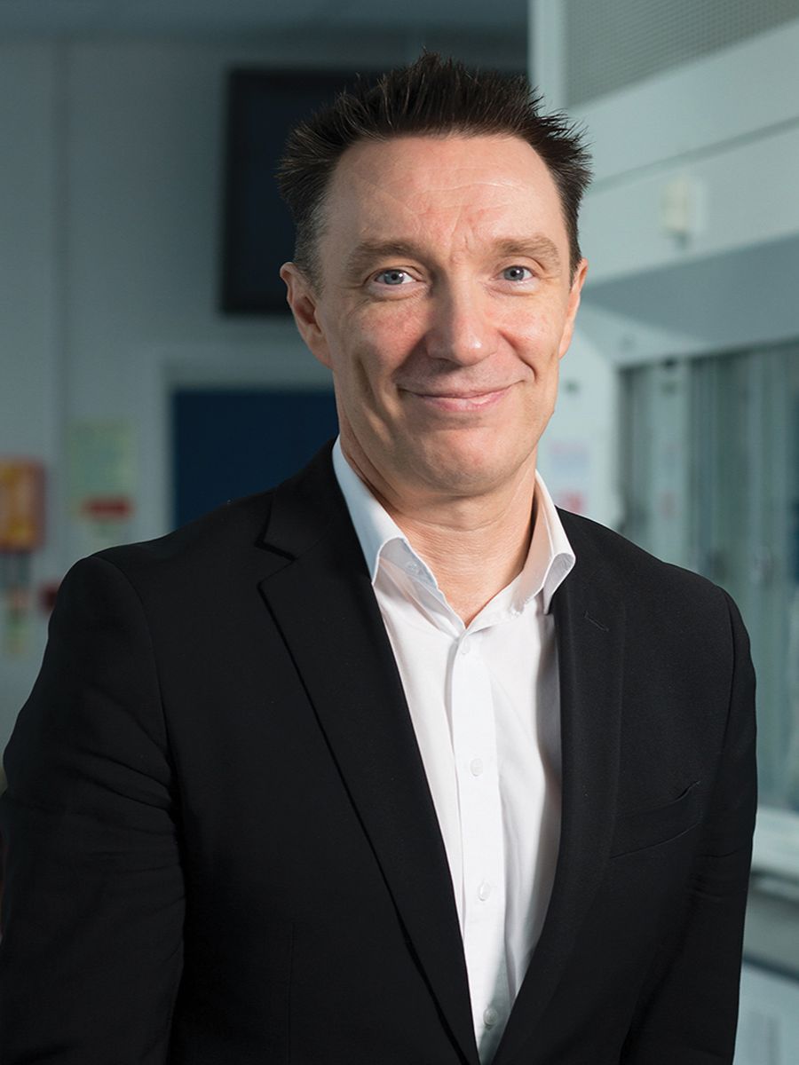 Andrew Cooper smiling to camera in black suit jacket and white shirt