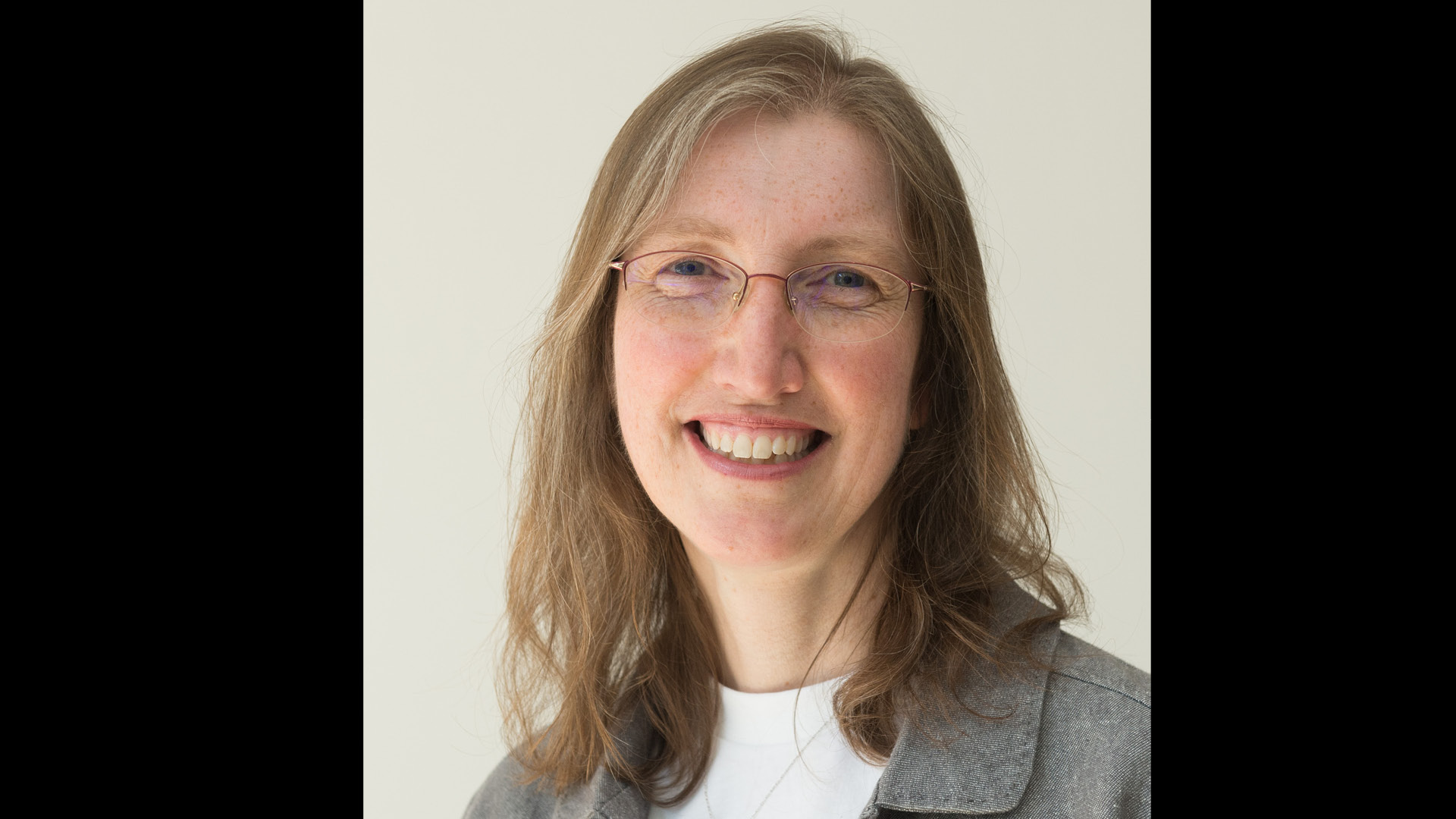 Team member Alison Trew Did You Know smiling to camera in white top and grey jacket