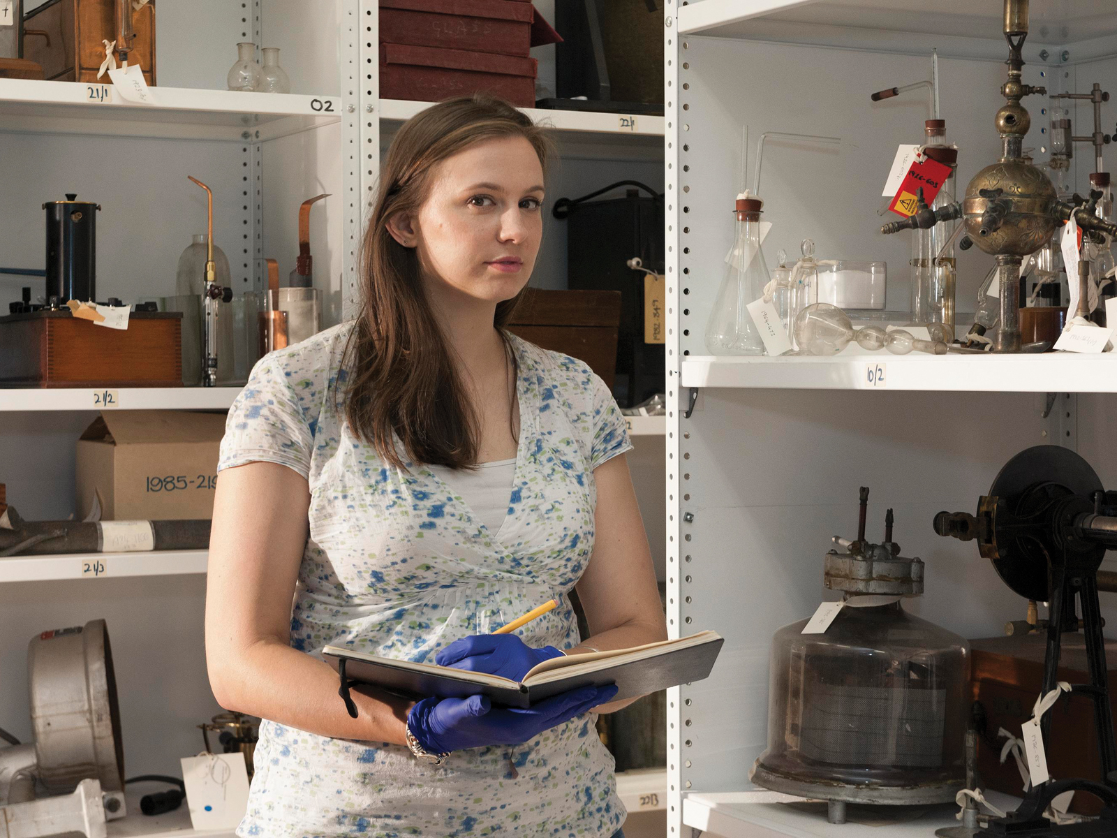 Sophie Waring surrounded by historical glassware and other scientific equipment