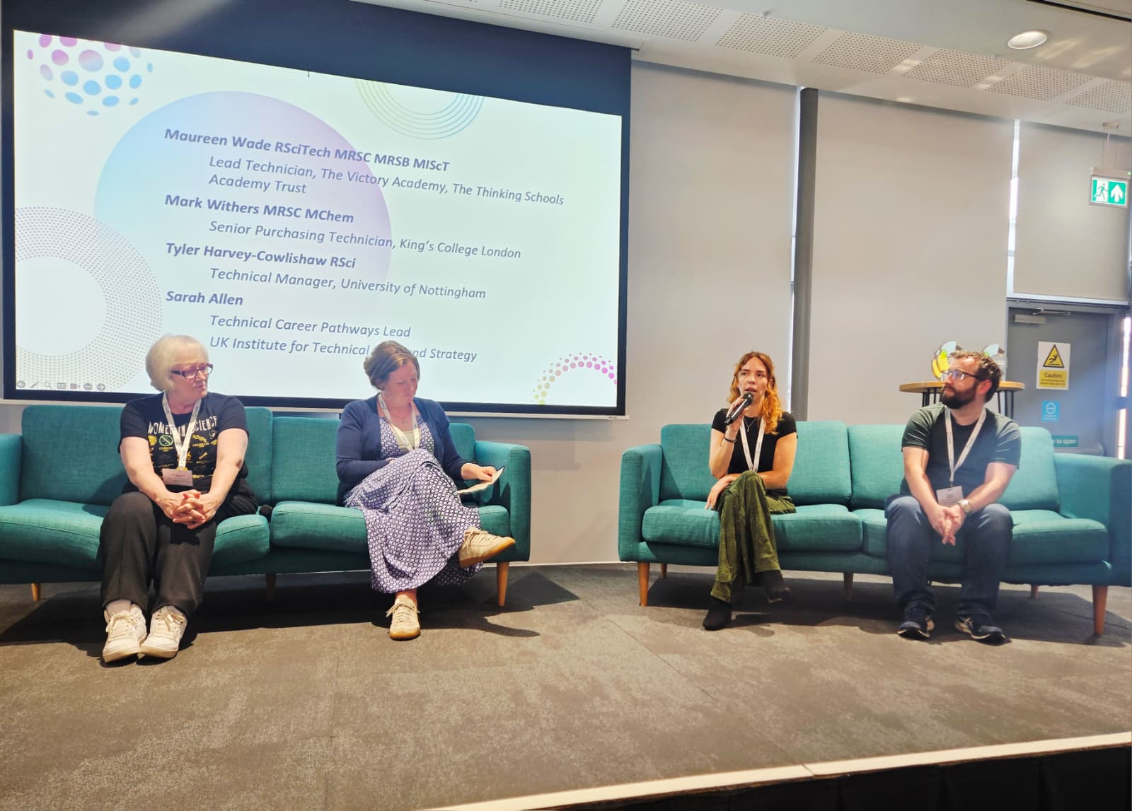 Four people sit on sofas on a stage during a panel discussion