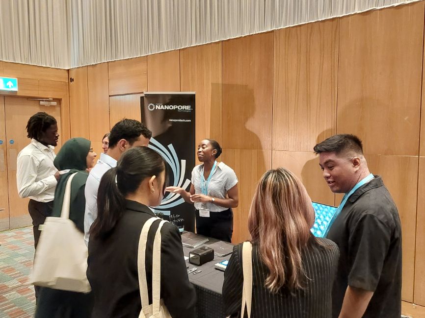 Students speak with representatives from Oxford Nanopore in front of a Oxford Nanopore hanging banner