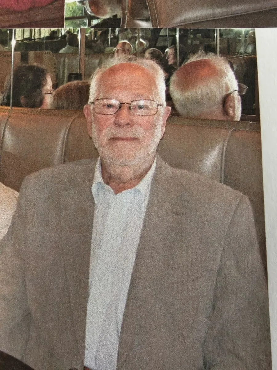 John Dewing deceased John Dewing in his later years sitting on leather chair in suit and shirt