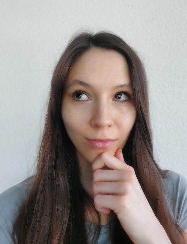 Karin Hrovatin looks thoughtfully upward and to her left, resting her chin on her hand against a plain background.
