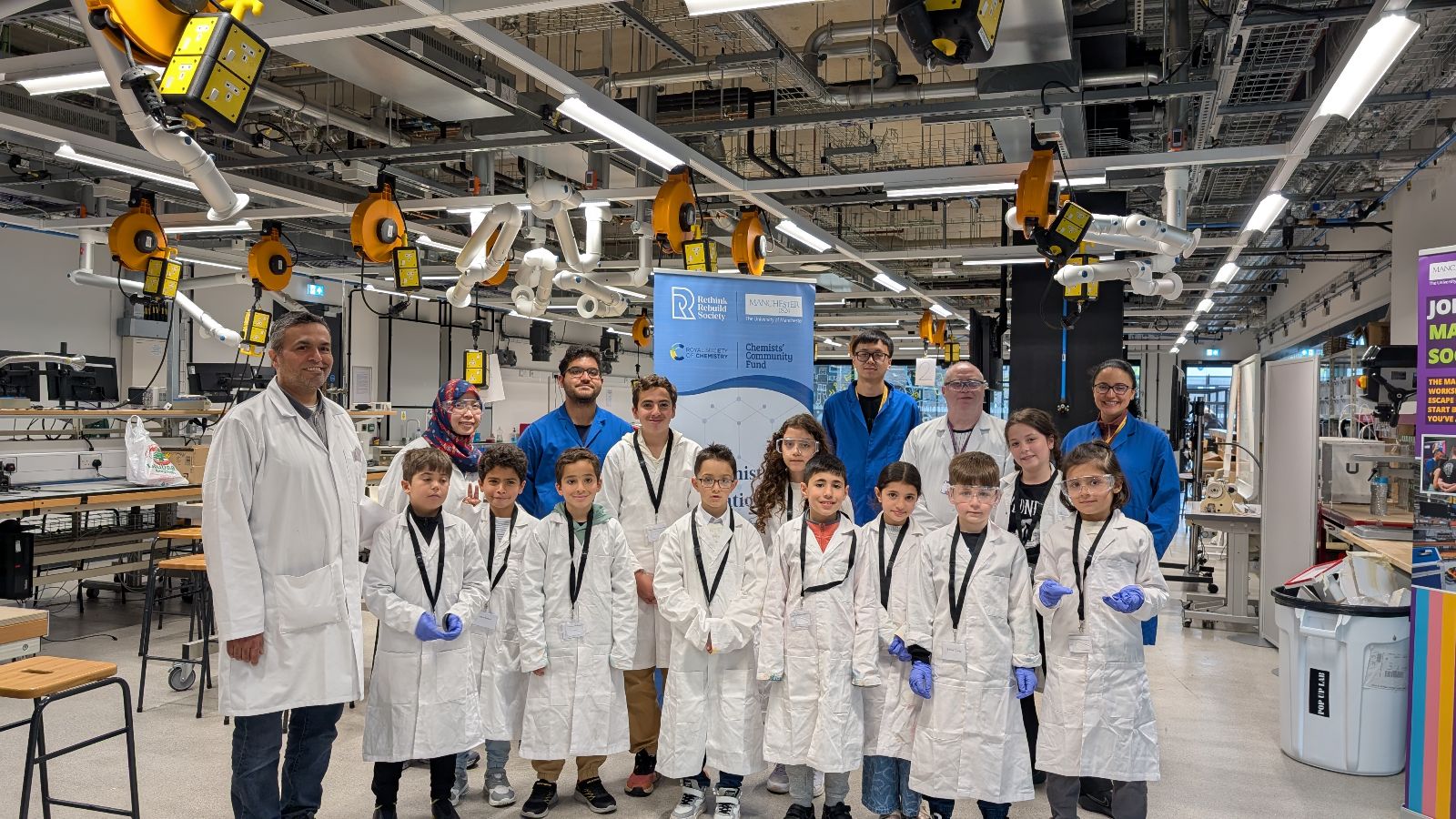 Chemistry workshop volunteers with the Syrian children in their lab coats and blue gloves