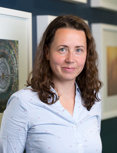 Headshot of Michaela Muehlberg smiling at the camera, wearing a blue shirt