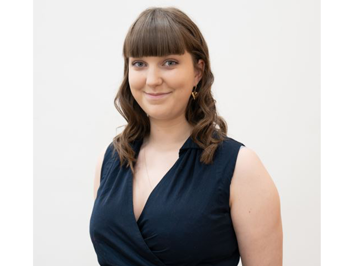Mia Outram in a black dress smiling for the camera