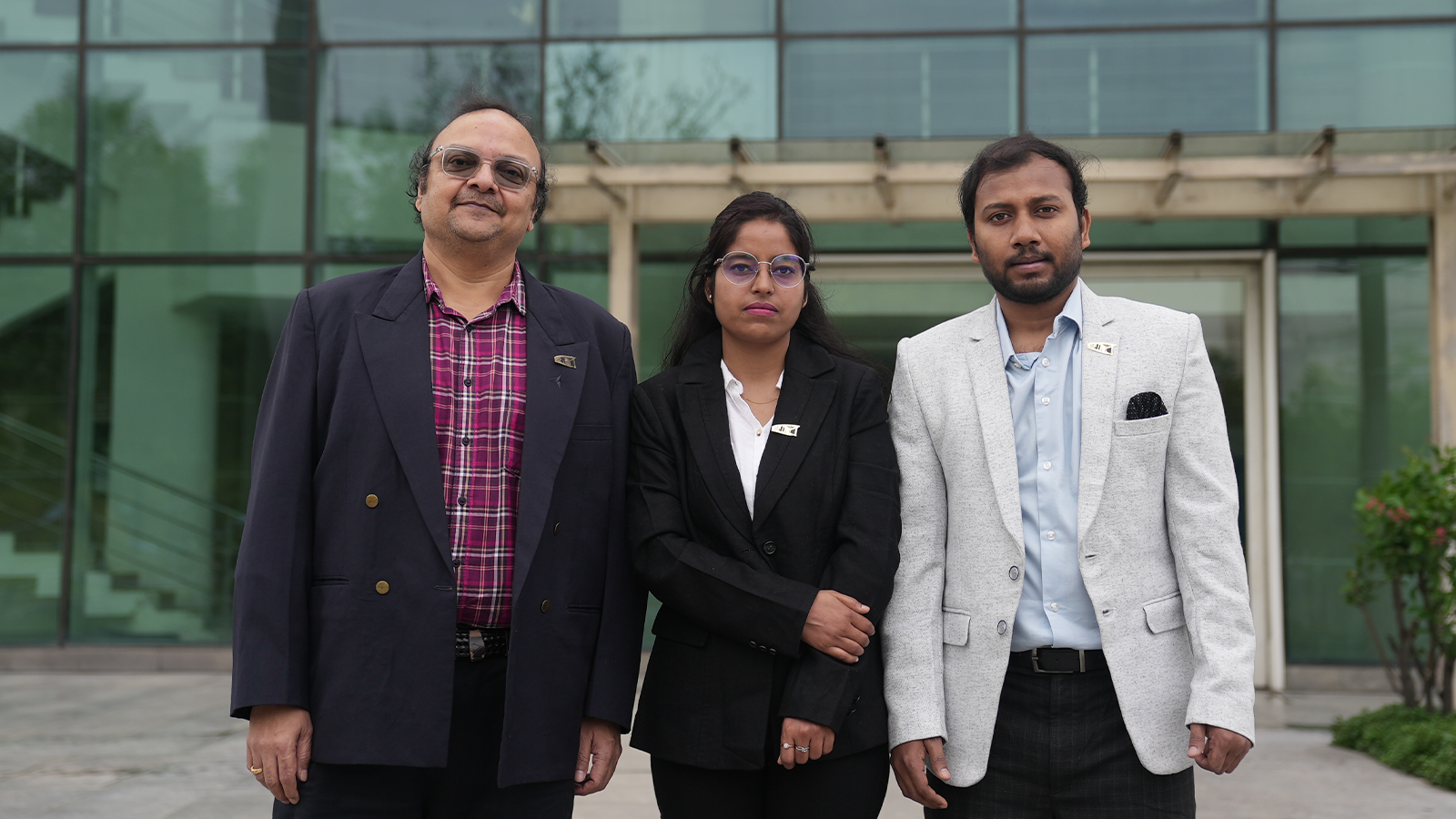 Three of AEEon Collective team in suits, standing outside their building
