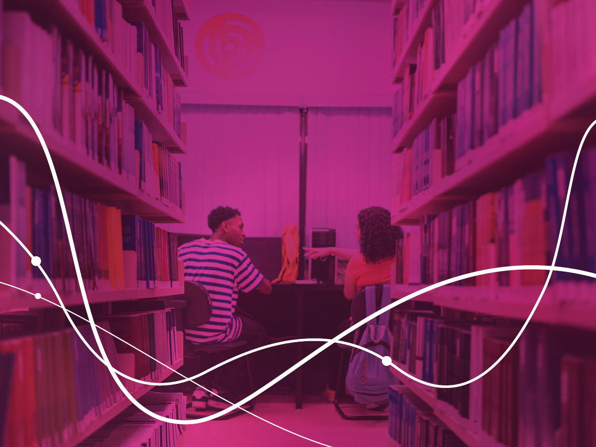 two people talking at a computer desk in a library