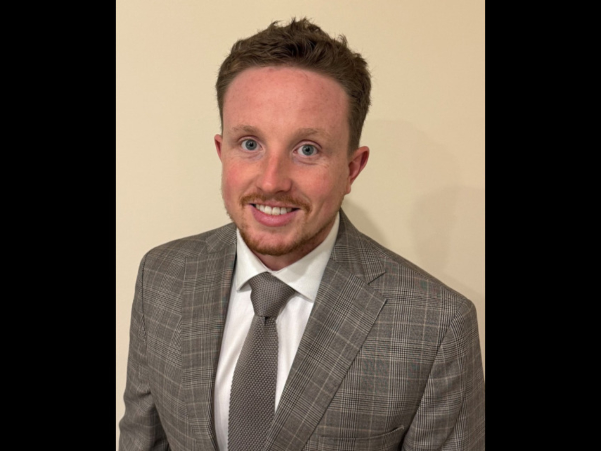 Liam Johnson smiling to camera in suit and tie