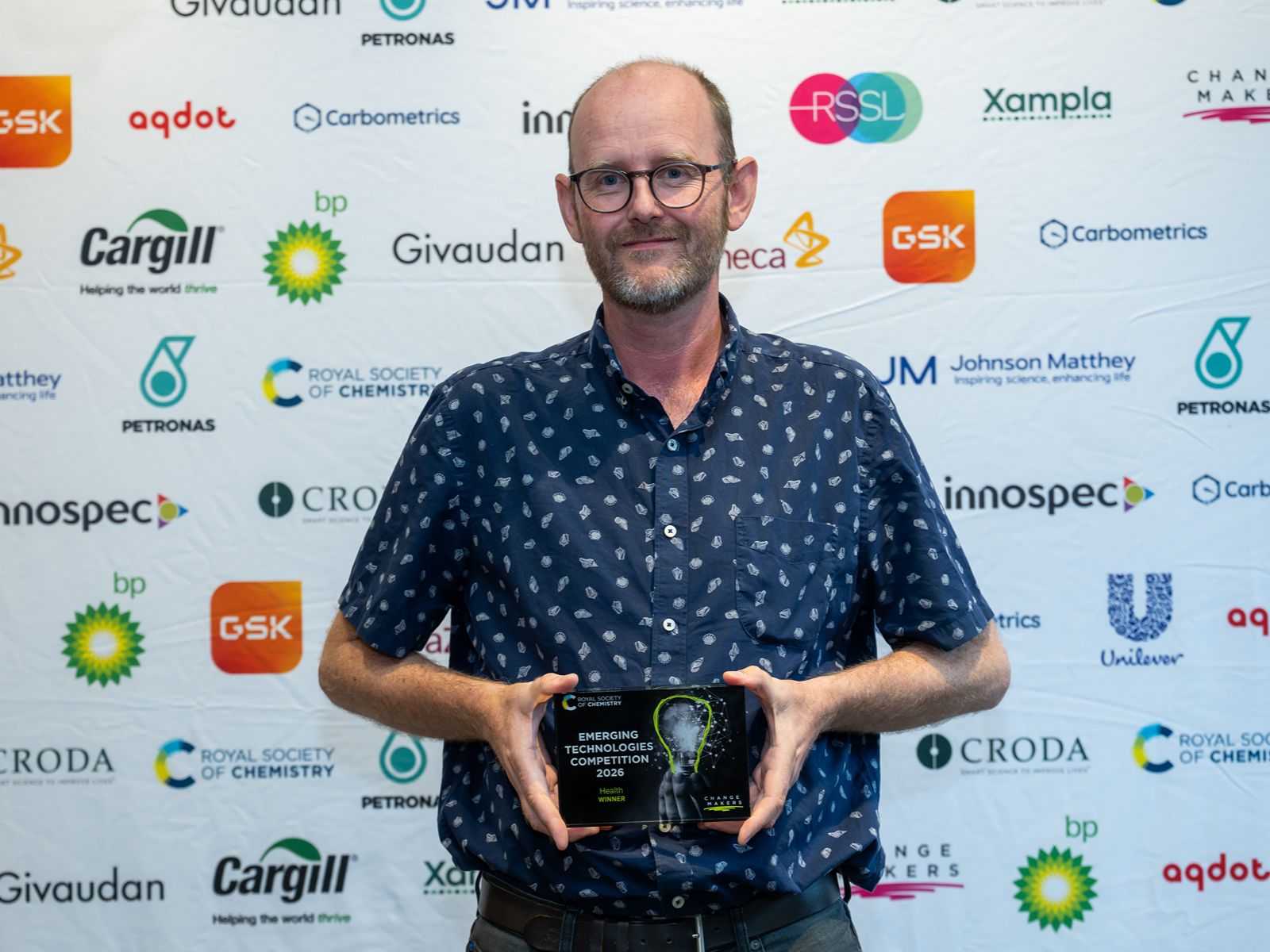 Jody Mason, chief science officer and founder of Revolver Therapeutics, smiles and holds an award