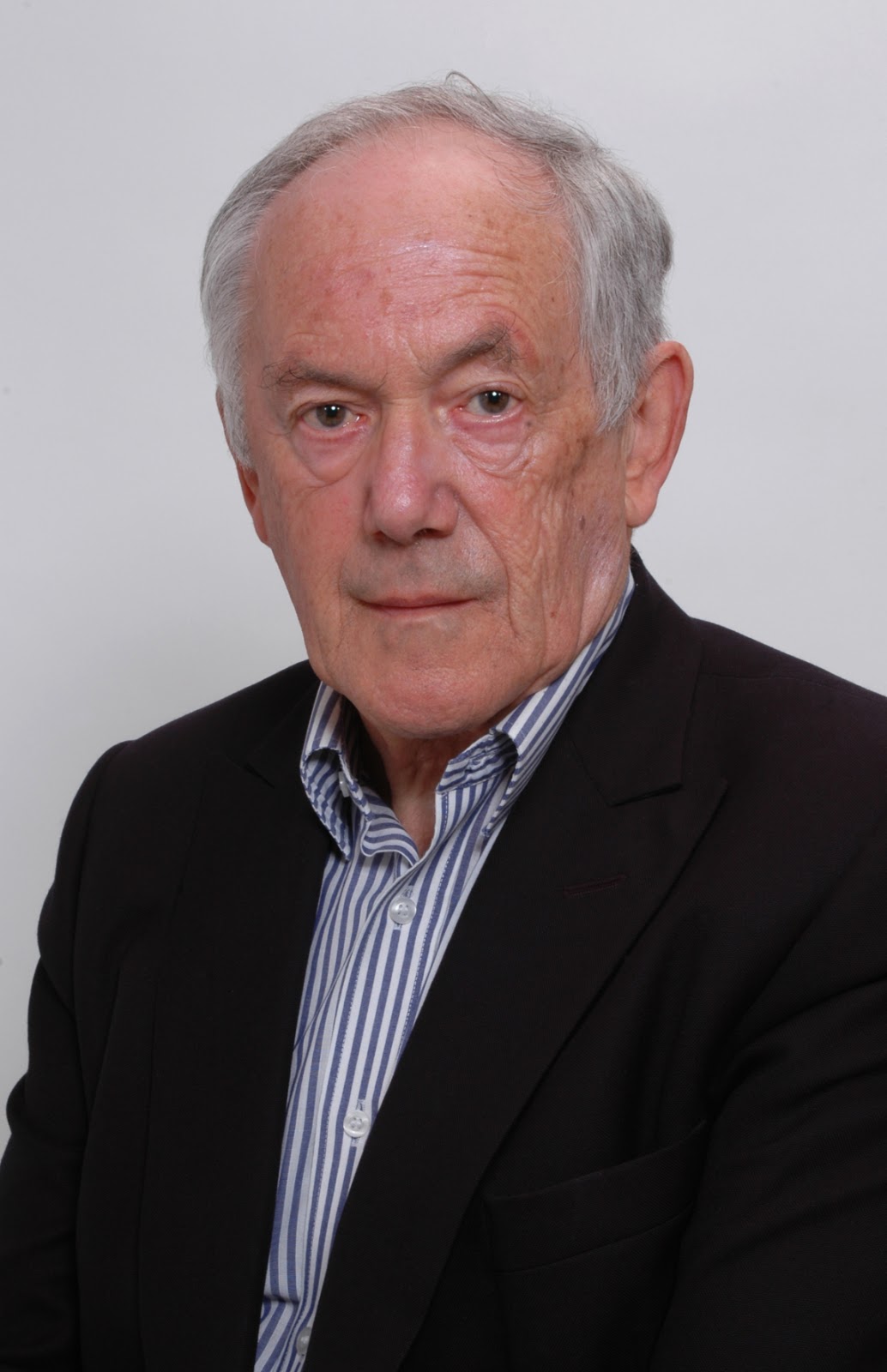 Peter Atkins in a black suit and a blue-and-white-striped shirt