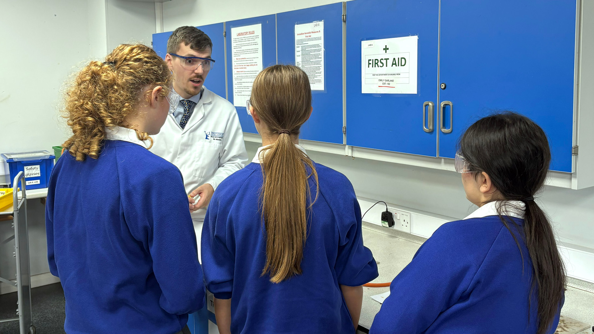 Matthew Gundry with school children in uniform in class room teaching science