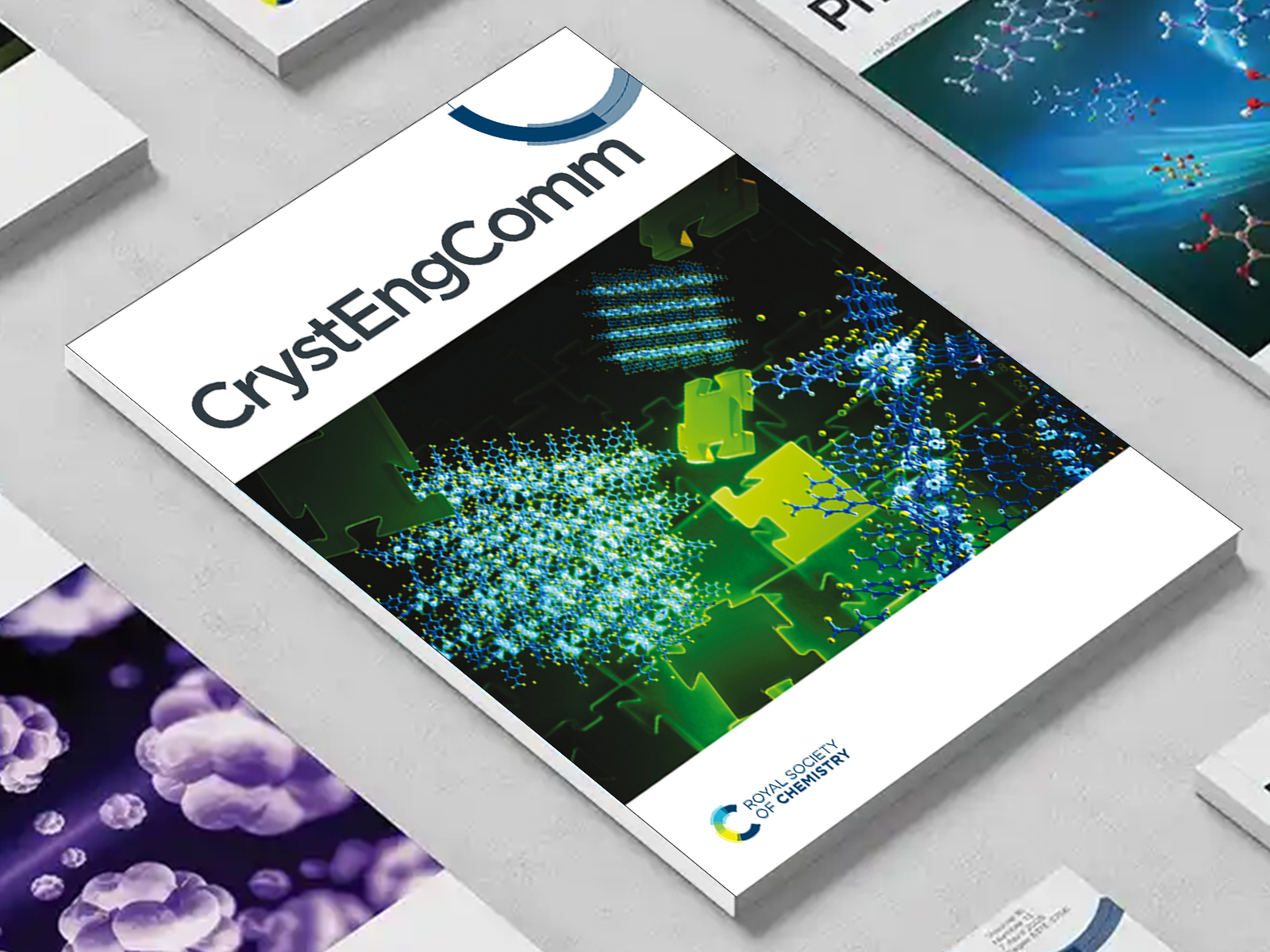 the CrystEngComm journal among a group of other journals on a desk