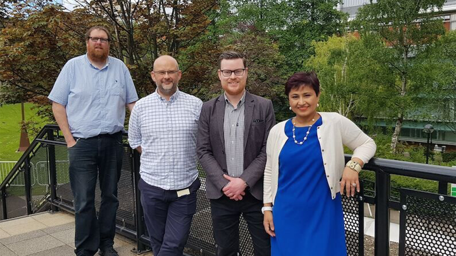 Professor Damion Corrigan and others facing camera outside near steps and greenery