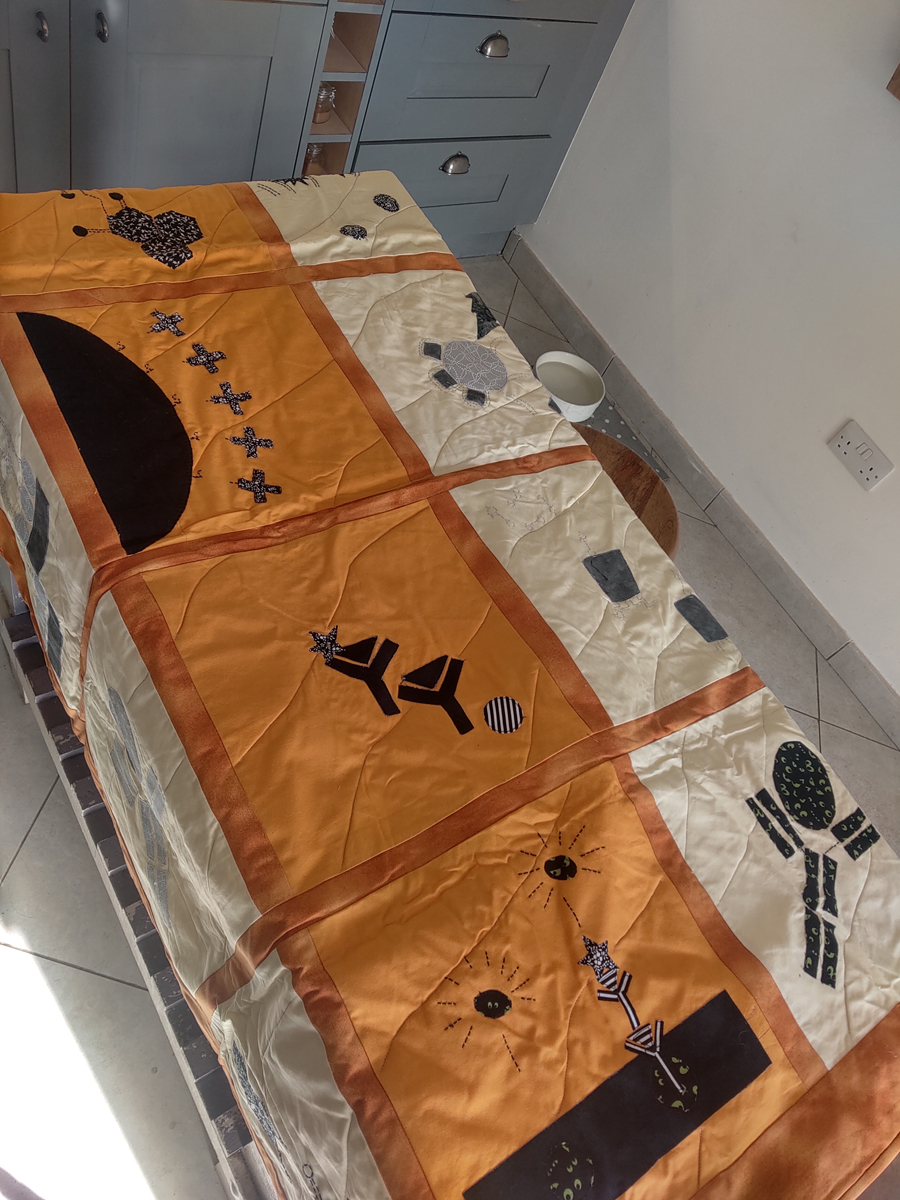 Orange quilt decorated with scientific symbols