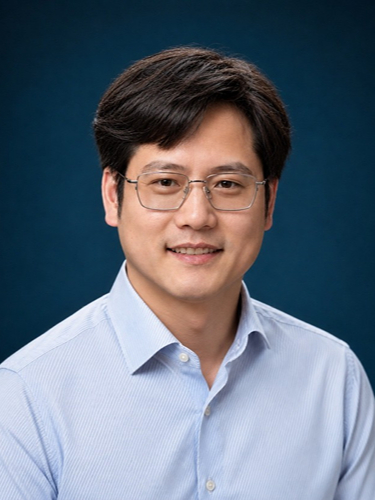 Qingshan Wei smiling wearing a light blue shirt and glasses against a dark blue background.