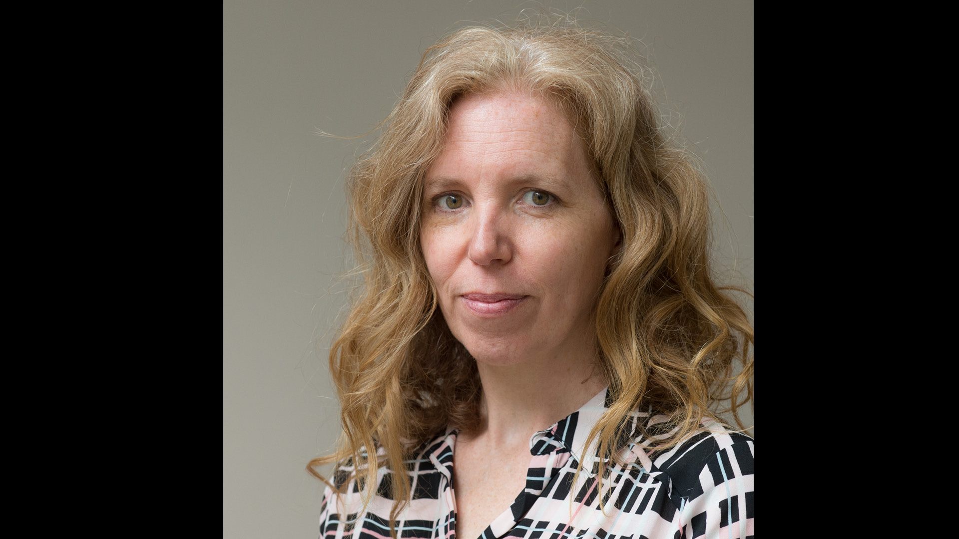 Rebecca Ellis team member of Did You Know smiling to camera in check shirt