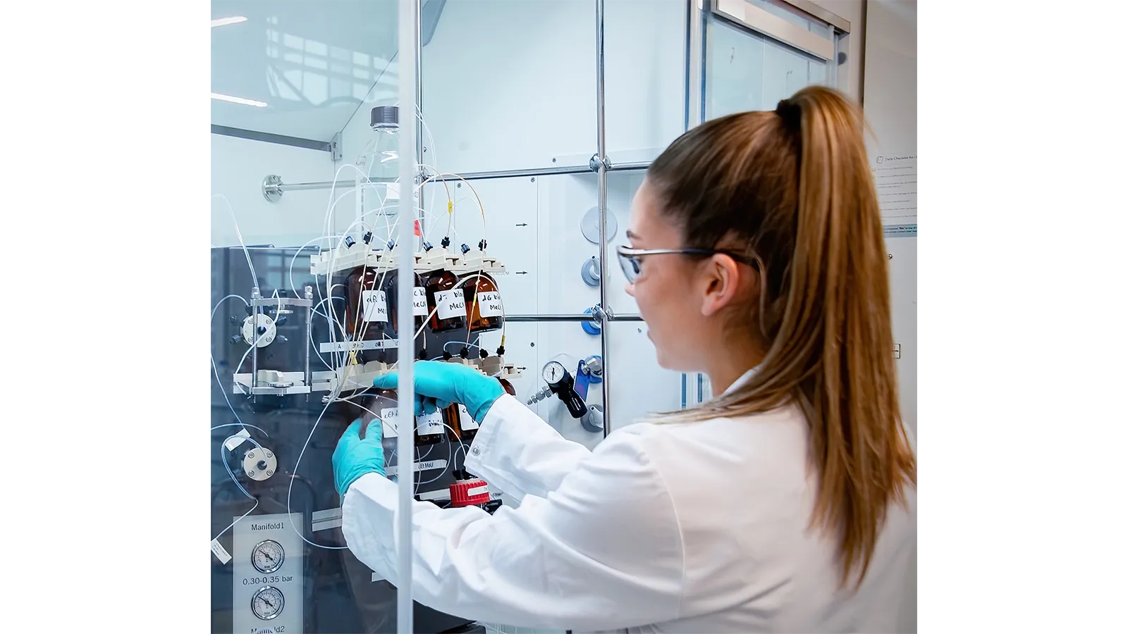 Georgia Wignall in in a lab coat and gloves working on a machine