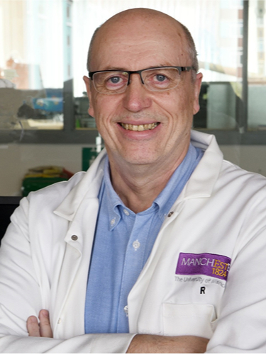 Professor David Leigh smiling wearing a white lab coat and glasses