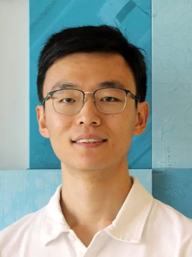 Shengwei Zhang Shengwei Zhang smiling wearing white polo shirt and glasses against a blue background.