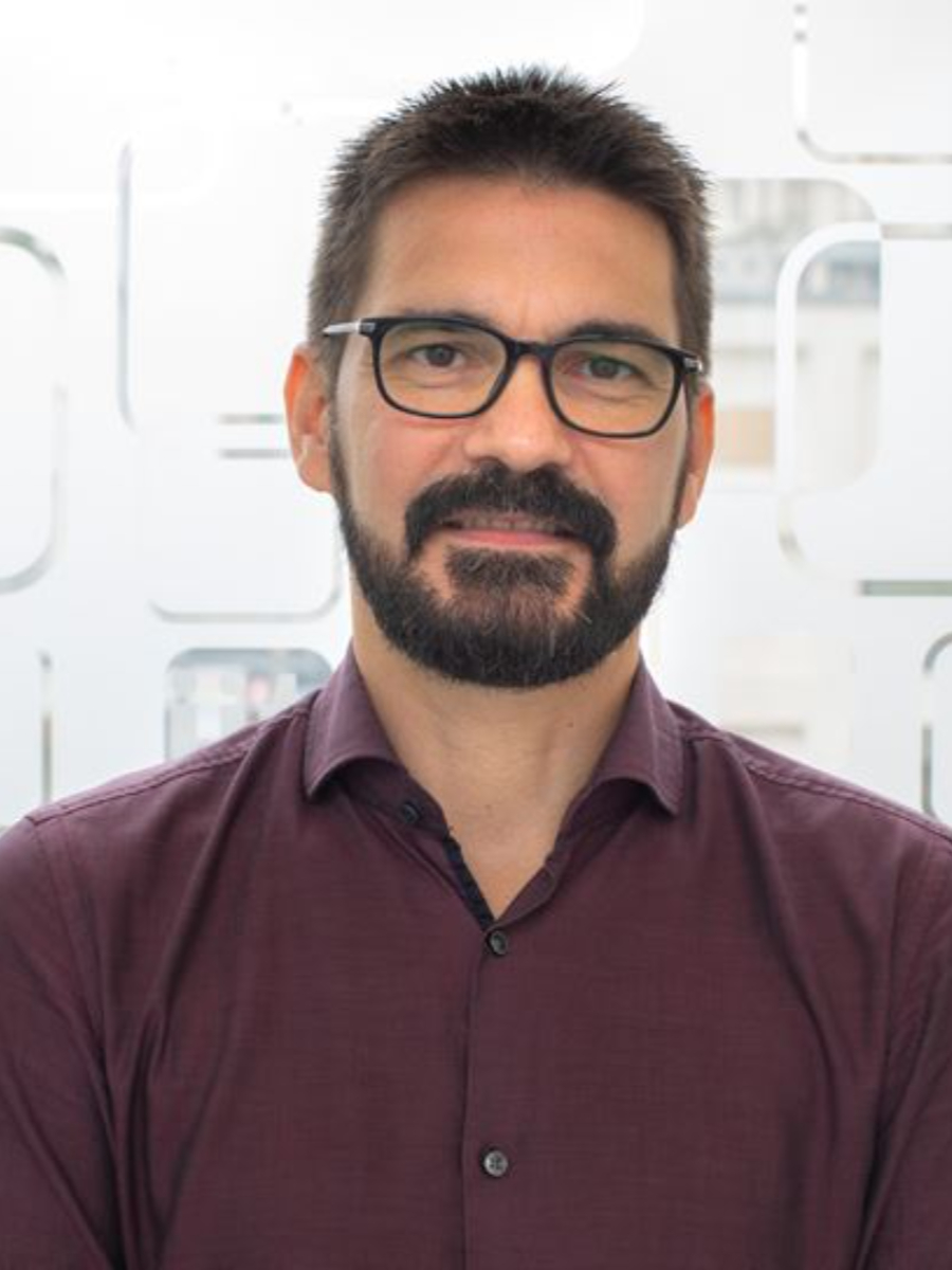Paolo Melchiorre to camera with beard and glasses and wearing a maroon shirt