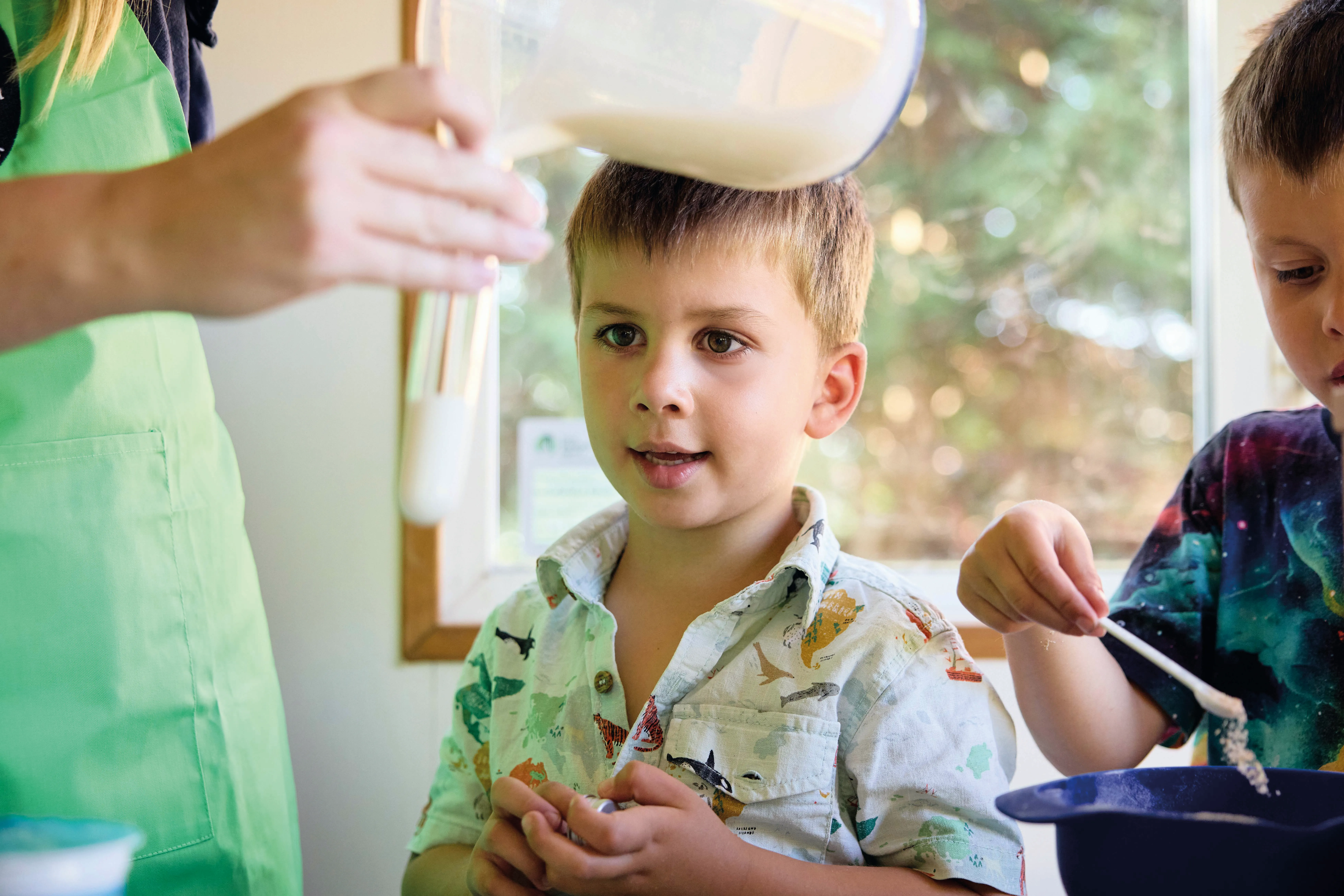 countryside-kitchen-PRINT-011 A boy looks wide-eyed at something in a test tube, while another pours something off a white plastic spoon
